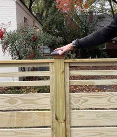 a person standing on top of a wooden fence