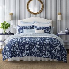 a bed with blue and white bedspread in a bedroom next to a mirror