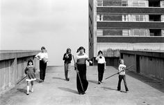 black and white photograph of four women holding baseball bats in front of an apartment building