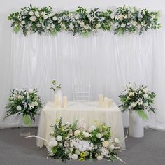 the table is set up with white flowers and greenery