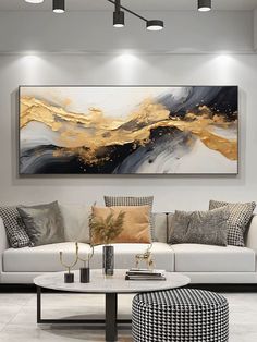 a living room with white couches and paintings on the wall above them, along with black and gold accents