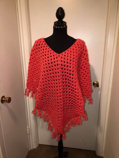 This poncho is done in Red Heart yarn in the color Flamingo. It measures 29" long in the front and back with the fringe and 24"long in both arms with the fringe.  shipping is free with this item. Casual One Size Poncho With Fringe, Casual One-size Poncho With Fringe, Spring Fringe Poncho One Size, One Size Poncho With Tassels In Cape Shape, Red Poncho For Beach In Fall, Red Fringed Shawl For Fall, Red Long Sleeve Poncho, One Size, Red Fringe Shawl For Fall, One Size Fringe Shawl Cape