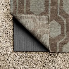 an area rug with a gray and brown design on it, next to a black mat