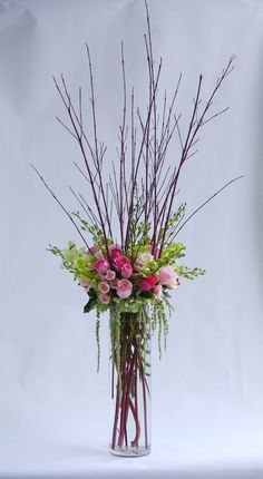 a vase filled with pink and green flowers on top of a white table next to a wall