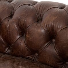 a brown leather couch with buttons on the armrests and back rest, in front of a white background