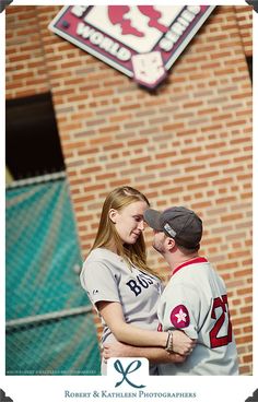 a man and woman standing next to each other in front of a brick building