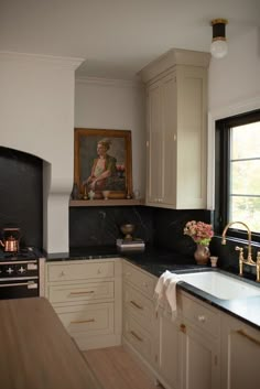 a kitchen with white cabinets and black counter tops, an oven and sink in front of a window