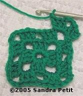 the crochet is green and has a small square on it with a hook