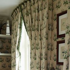 the curtains in this room are lined with green leaves and flowers, along with pictures on the wall