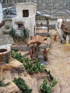 an outdoor area with cactus, rocks and small buildings in the background on a cloudy day