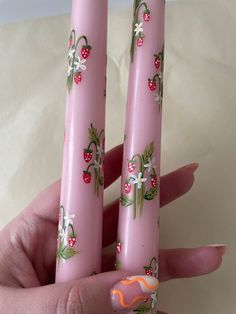 two pink candles with flowers and berries painted on them