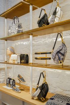 several purses and handbags are on display in a store shelf with wooden shelves