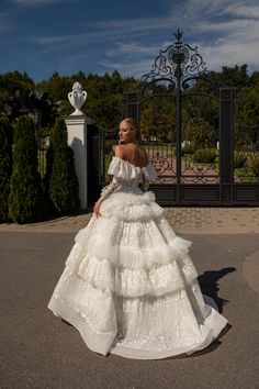 a woman in a white wedding dress standing on the street with her hands behind her back