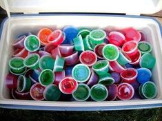 there are many different colored cups in the container on the grass and one is filled with them