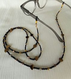 Sunglasses chain Eyeglasses chain Glasses chain This beautiful chain for glasses is made of small glass beads 2 mm in black, combined with hematite beads 4 mm in bronze and gold   shades. Hematite bronze hearts are 6-7 mm in diameter. At the end of the chain are gold plated buckles on which are silicone rubber glasses holders. If you remove the silicone rubber bands, the chain can also be a mask holder. The chain is effective and modern, it can be a very nice Christmas gift. If you buy this chai Trendy Black Metal Glasses Chains, Metal Glasses Chains As Gift, Adjustable Beaded Black Glasses Chains, Adjustable Black Beaded Glasses Chains, Elegant Black Glasses Chains For Party, Gold Glass Party Glasses Chains, Beaded Metal Glasses Chains For Party, Metal Beaded Glasses Chains For Party, Trendy Adjustable Glasses Chains As Gift