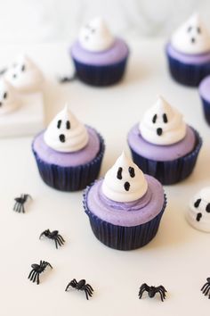 cupcakes with white frosting and black sprinkles are arranged on a table