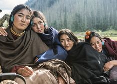 three women sitting next to each other on the ground