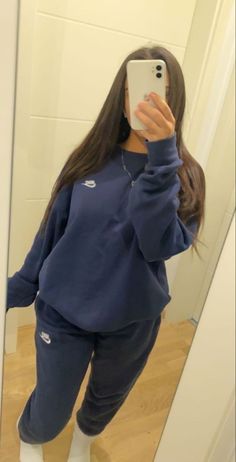 a woman taking a selfie in front of a mirror wearing sweatpants and sneakers