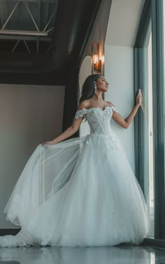 a woman in a white wedding dress leaning against a wall with her arms outstretched and looking up at the sky