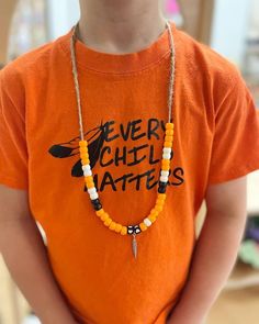 a young boy wearing an orange shirt with a beaded necklace on it's neck