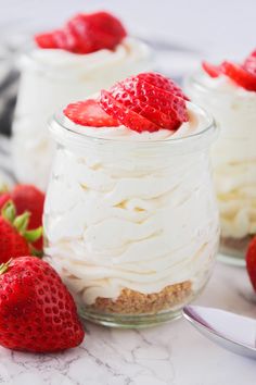 three small jars filled with whipped cream and strawberries