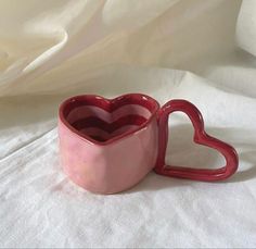 two heart shaped mugs sitting on top of a white sheet