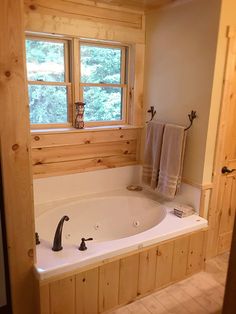 a large jacuzzi tub in the corner of a bathroom with wood paneling