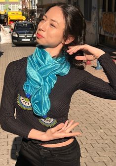 "We name this scarf \"AŞKLA\" which means \"With Love\"!. The moment you own it, you fall in love with it... The scarf of AYDIN EFE OYA, from the Aegean region of Anatolia, has been with us since the day we set out. It is known as the \"queen\" of traditional needlework productions. The needle lace at both ends of the silk scarf is fan-shaped and has small silver sequins knitted on them throughout the frame of the lace.  The silk fabric used for this scarf is delicate and beautiful. Its color is turquoise blue, blue as the Aegean Sea!  This scarf is lively and feels so fresh.  You can wear it for receptions, dinners, parties, or during the day with dresses, white blouses, and blazers or suits.  We shot the photos with our model Ayşe, who is also a ballerina on the streets -we love- of beau Artistic Handmade Blue Silk Scarf, Turquoise Blue Scarf, Turquoise Scarf, Bohemian Purple Silk Shawl Scarf, Luxury Artistic Blue Silk Scarf, Blue Silk Scarf, Needle Lace, Silver Sequin, Bleu Turquoise