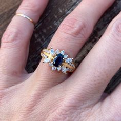 a woman's hand with two gold rings and an engagement ring on her finger