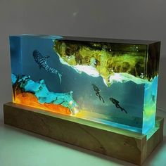 an aquarium with some fish in it and people swimming around the bottom one is made out of plexed wood