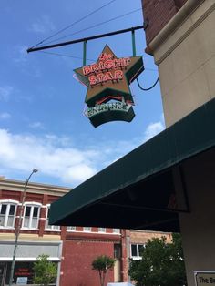 the sign is hanging from the side of the building that houses the bar and grill