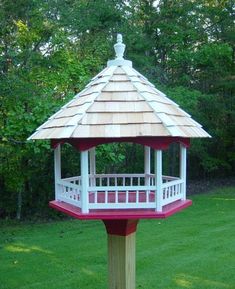 a white and red gazebo sitting on top of a lush green field