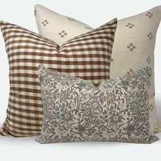 three pillows with different patterns on them, one is brown and the other is white