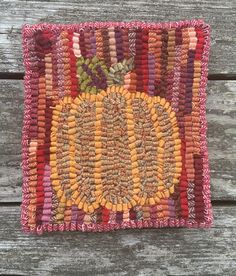 an orange and yellow rug on top of a wooden table next to a piece of wood