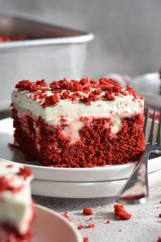 a slice of red velvet cake with white frosting and sprinkles on a plate