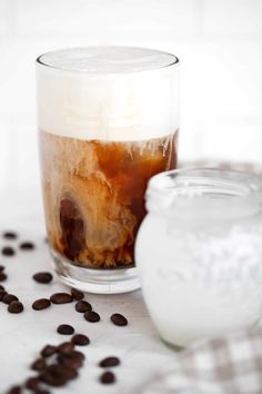 an iced drink in a glass next to coffee beans