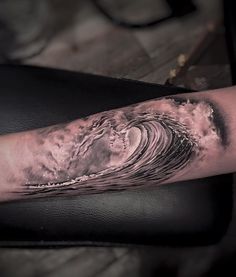 a man's arm with an ocean wave tattoo on the inside of his arm