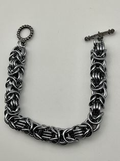 This byzantine rope chain bracelet is simple in its design. It is also lightweight, and holds up well. The design is such that it would look good on a large or small wrist size, just be sure to specify the desired length in the personalization options. This is annodized aluminum, making it lightweight, and the black ice color gives it a hint of blue or purple in the right lighting. Charms can be added - message me to start a custom order. Everyday Silver Metal Braided Bracelets, Silver Metal Box Chain Bracelet, Silver Link Bracelet With Jump Ring, Metal Link Bracelets With Jump Ring, Handmade Metal Chain Bracelet With Rectangular Links, Handmade Chain Bracelet With Rectangular Metal Links, Brutalist Design, Bracelets Design, Design Bracelet