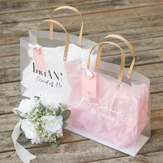 two bags with flowers are sitting on a wooden table and one has a white flower in it