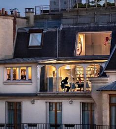 an apartment building with the roof lit up at night and people standing on the balcony