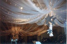 the ceiling is decorated with white lights and stars hanging from it's netted fabric