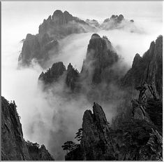 black and white photograph of mountains covered in fog