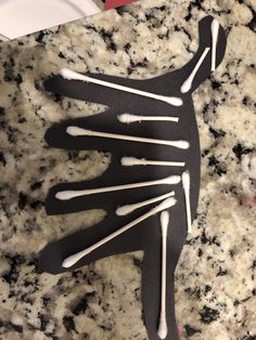 a paper cut out of the shape of a human body on a marble surface with white and black paint