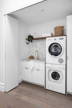 a washer and dryer in a small room with white cabinets, wood flooring