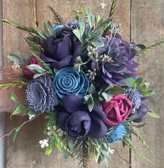 a bouquet of purple and blue flowers in front of a wooden wall