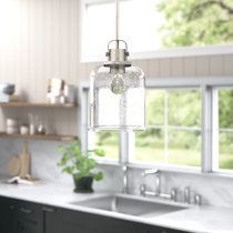 two lights hanging over a kitchen sink next to a counter top and window with open windows