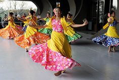 a group of women in brightly colored dresses dancing