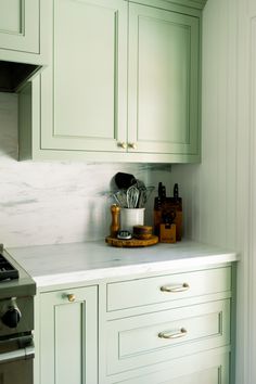 a kitchen with green cabinets and white marble counter tops, an oven and stove top