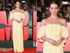 a woman in a yellow dress posing for pictures on the red carpet at an event