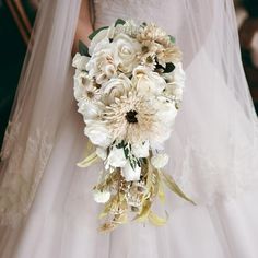 a bridal holding a bouquet of white and beige flowers on her wedding day,